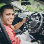 Quadriplegic man sitting in the seat of his customised control car. He is smiling for the camera.