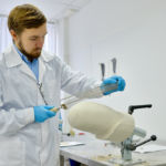 Portrait of young prosthetics technician sanding prosthesis molds while working in modern design laboratory, copy space