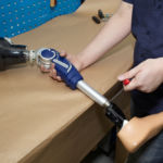 Worker in orthopaedic workshop adjusts leg prosthesis.
